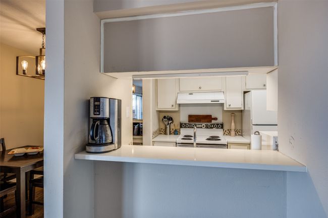 Kitchen with white appliances, under cabinet range hood, white cabinetry, and a peninsula | Image 5
