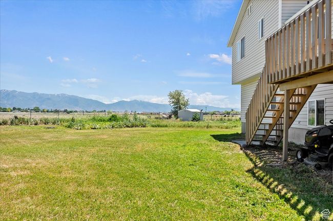 View of green lawn featuring stairs, a deck with mountain view, and a view of countryside | Image 25