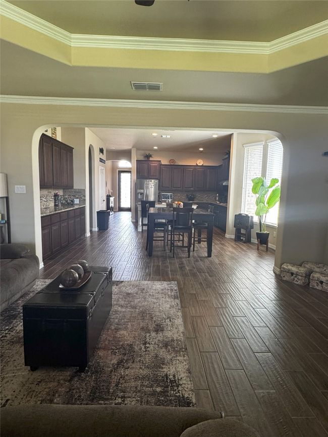 Living area featuring dark wood-type flooring, ornamental molding, arched walkways, and a raised ceiling | Image 21