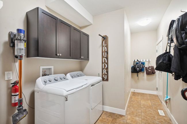 Laundry area featuring baseboards, light tile patterned flooring, visible vents, independent washer and dryer, and cabinet space | Image 35