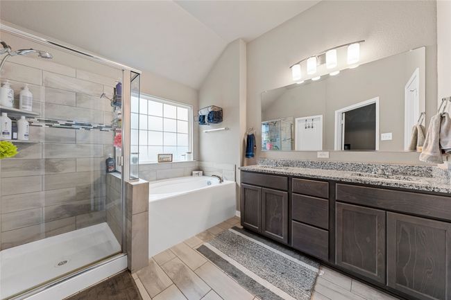 Bathroom with a stall shower, a garden tub, double vanity, vaulted ceiling, and wood finish floors | Image 19