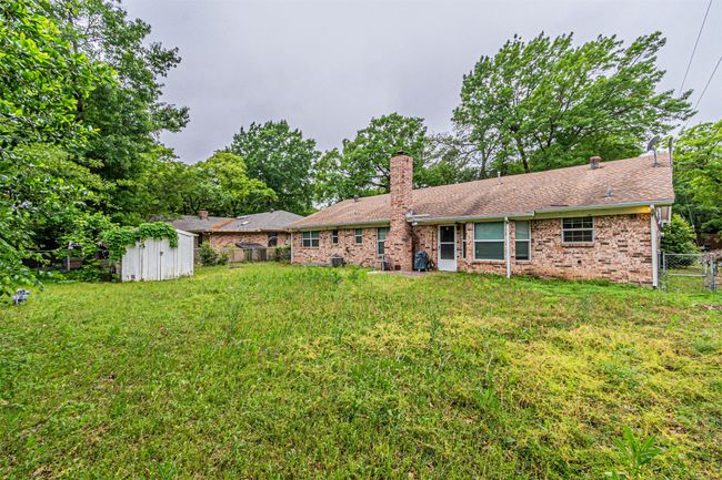 Rear view of house with a chimney, fence, an outbuilding, a storage shed, and a lawn | Image 31