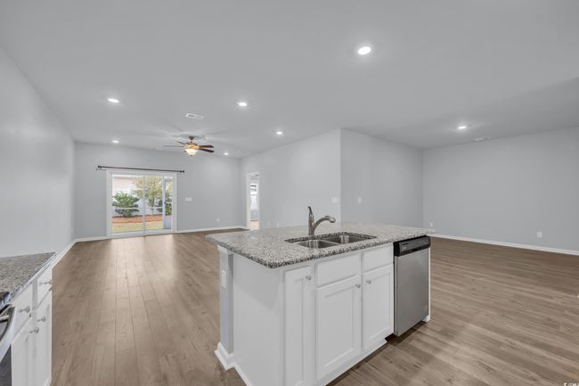 Kitchen with a center island with sink, a sink, light wood-style floors, appliances with stainless steel finishes, and open floor plan | Image 7