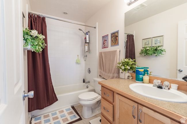 Bathroom with vanity, shower / bath combo with shower curtain, toilet, visible vents, and tile patterned flooring | Image 18