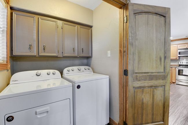 Washroom featuring cabinet space, washer and clothes dryer, and wood finished floors | Image 14