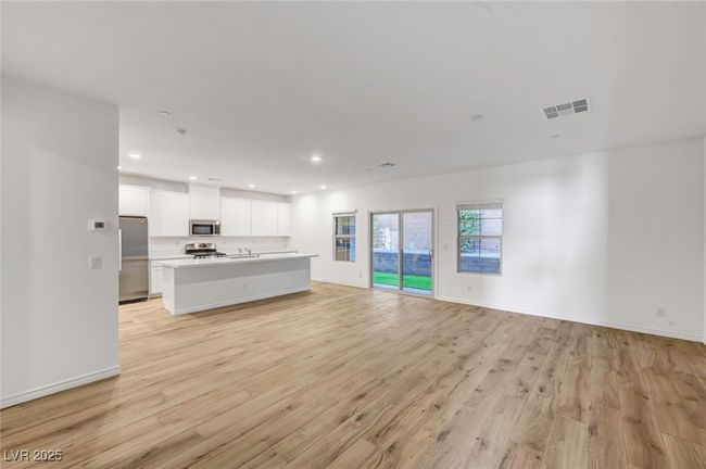 Unfurnished living room with light wood finished floors, recessed lighting, and visible vents | Image 6