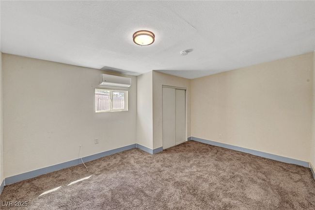 Unfurnished bedroom with a wall unit AC, carpet, a closet, and a textured ceiling | Image 33