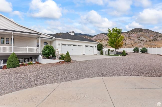 View of side of home featuring an attached garage, a mountain view, concrete driveway, and covered porch | Image 103