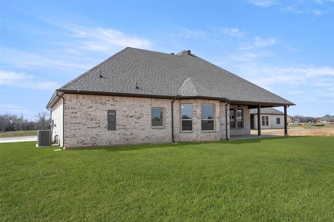 Back of property featuring roof with shingles, a yard, brick siding, and central AC | Image 26