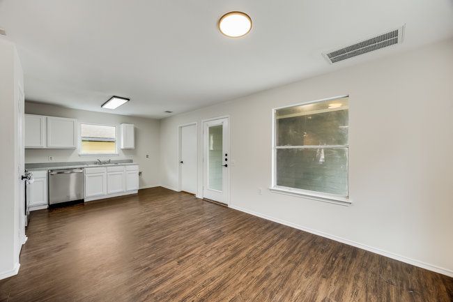 Kitchen featuring stainless steel dishwasher, dark wood-style flooring, white cabinetry, baseboards, and a sink | Image 17