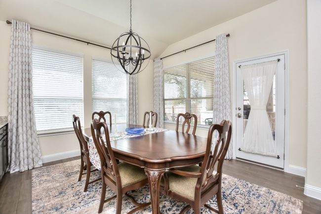 Dining space with lofted ceiling, a notable chandelier, dark wood-style floors, and baseboards | Image 5