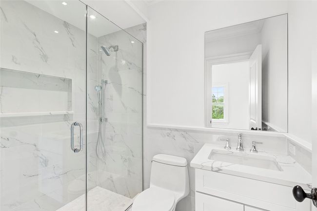 Full bath featuring a marble finish shower, vanity, tile walls, and wainscoting | Image 42