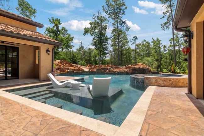 Covered patio to left has outdoor gas hookup, double iron doors lead into game room/kitchen area. Pool has built in seating. | Image 5