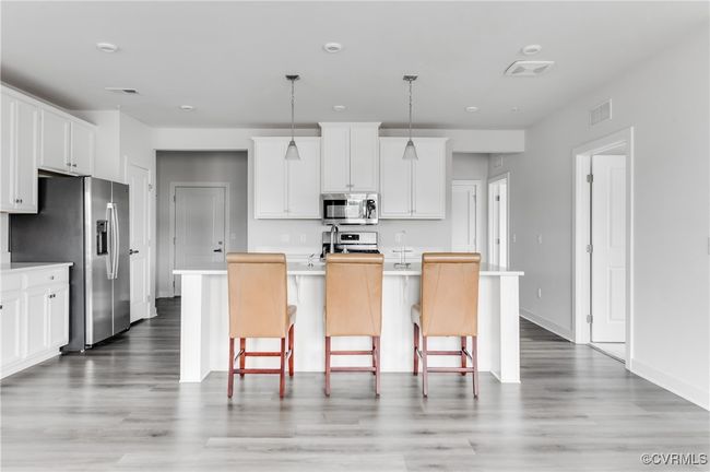 Kitchen with stainless steel appliances, light wood-style flooring, and white cabinetry | Image 8