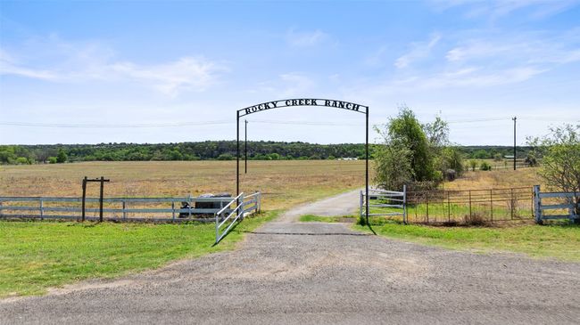 View of street featuring a gated entry, a gate, driveway, and a rural view | Image 5