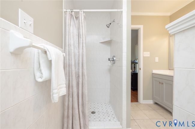 Bathroom featuring tiled shower, tile patterned floors, vanity, and ornamental molding | Image 25