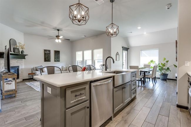 Kitchen with stainless steel dishwasher, a sink, a healthy amount of sunlight, a center island with sink, and gray cabinetry | Image 34