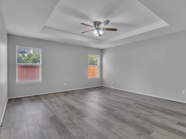 Spare room featuring a raised ceiling, ceiling fan, healthy amount of natural light, and wood finished floors | Image 17