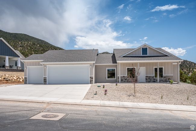 View of front of house featuring stone siding, an attached garage, driveway, roof with shingles, and a mountain view | Image 4