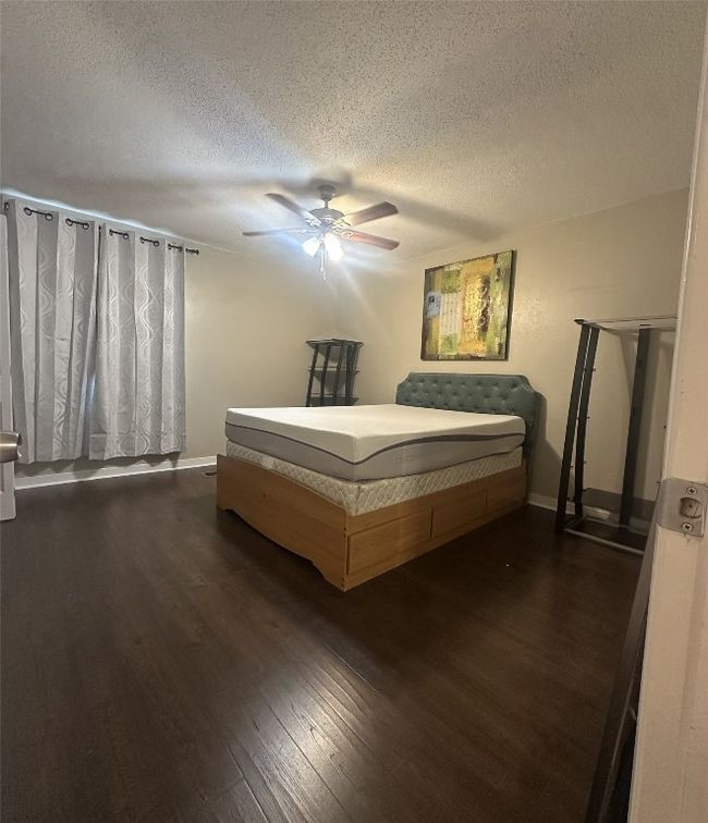 Bedroom with dark wood-style floors, a textured ceiling, ceiling fan, and baseboards | Image 19
