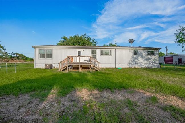Enjoy relaxing on the inviting porch while taking in the serene landscape around you, complete with lush grass and vibrant trees. | Image 33