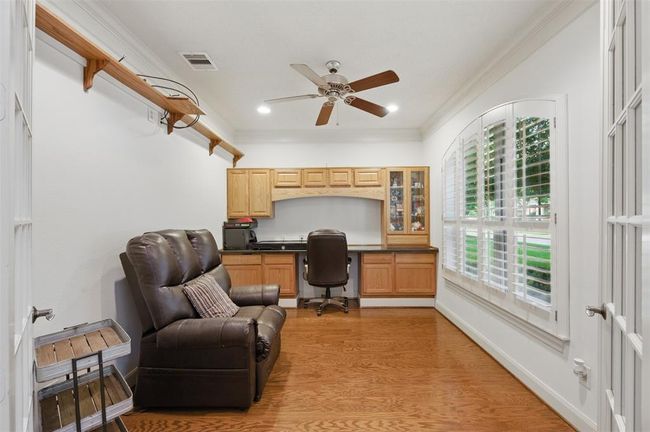 To your right as you enter the home, you will find the private study also with rich hardwoods and crown molding. A built-in desk and glass paneled French doors completes the space. | Image 9