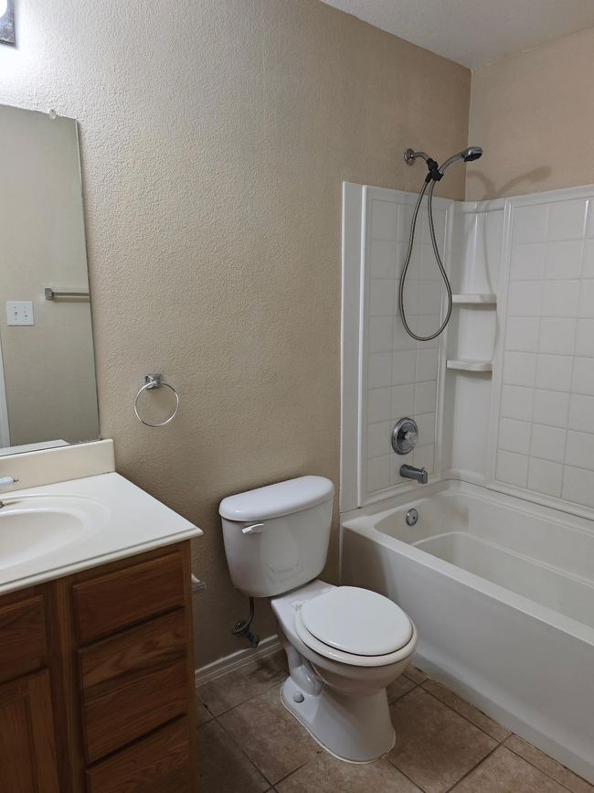 Bathroom with toilet, tile patterned flooring, vanity, and bathing tub / shower combination | Image 4