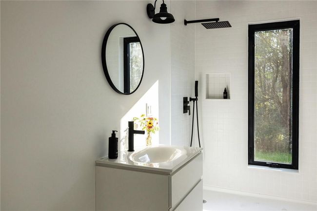 Bathroom with a healthy amount of sunlight, vanity, and tiled shower | Image 11