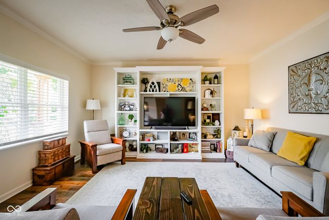 living room featuring wood finished floors, a ceiling fan, ornamental molding, and baseboards | Image 7