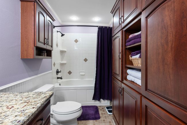 Bathroom with ornamental molding, vanity, shower / bath combination with curtain, wainscoting, and tile patterned floors | Image 13
