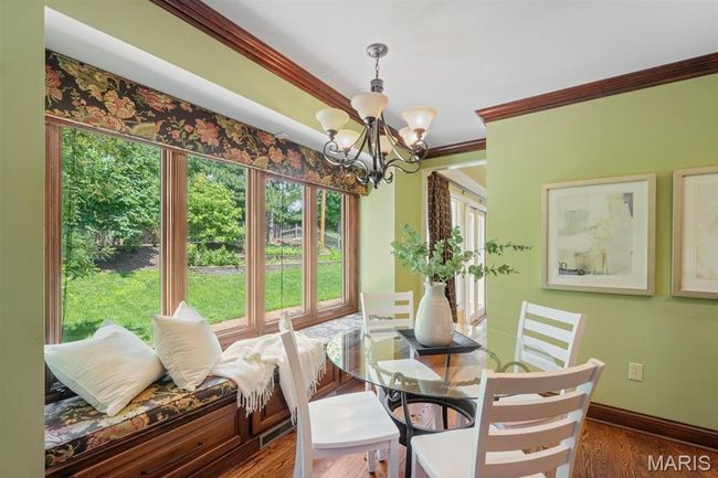 Dining space featuring a chandelier, healthy amount of natural light, crown molding, and wood finished floors | Image 17