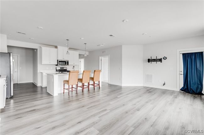 Kitchen with appliances with stainless steel finishes, a center island with sink, light wood finished floors, light countertops, and white cabinets | Image 7