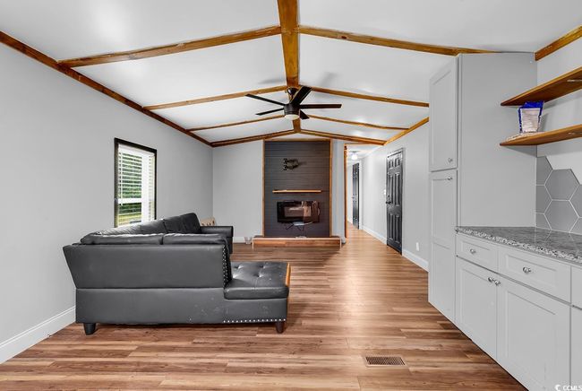 Empty room with wooden walls, ceiling fan, a textured ceiling, vaulted ceiling, and wood finished floors | Image 18