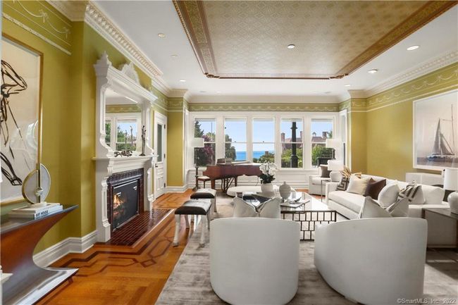THE LIVING ROOM PARLOR // Warm and inviting with expansive water views, open to veranda, wood burning fireplace with gas assist, detailed crown molding, mahogany windows and door. Perfect for intimate gathering or opens to the front parlor for large gatherings. | Image 6