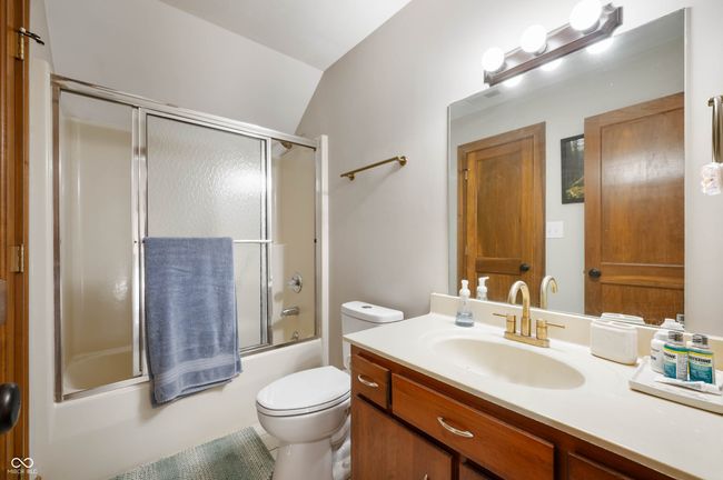 full bath featuring bath / shower combo with glass door, vaulted ceiling, vanity, and toilet | Image 31