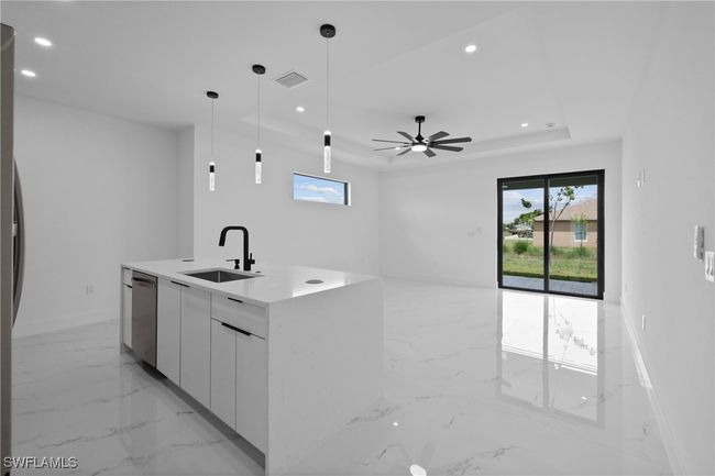 Kitchen with stainless steel dishwasher, light marble finish flooring, a sink, modern cabinets, and recessed lighting | Image 12