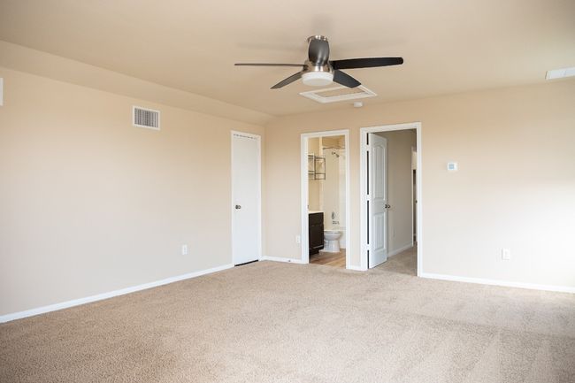 Unfurnished bedroom featuring light colored carpet, baseboards, ensuite bathroom, and a ceiling fan | Image 20