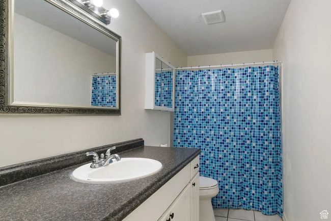 Full bath with a shower with curtain, tile patterned flooring, and toilet | Image 9