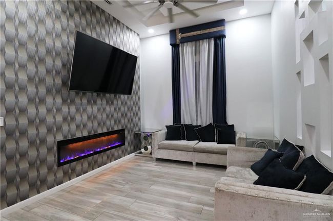 Living area with a large fireplace, a ceiling fan, wood finished floors, and recessed lighting | Image 7