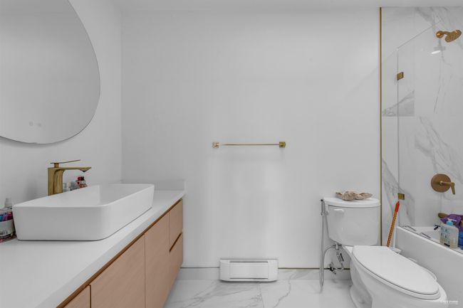 Full bath with marble look tiles, vanity, toilet, tub / shower combination, and a baseboard heating unit | Image 20