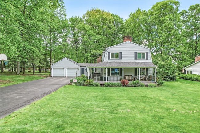 Beautiful home with a spacious front porch and a two-car garage, surrounded by mature trees. | Image 4