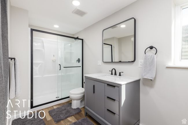 Bathroom featuring wood finished floors, a stall shower, vanity, toilet, and visible vents | Image 29