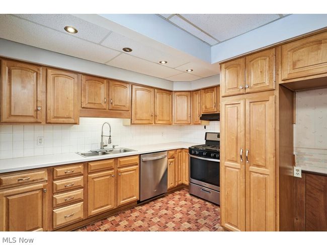 Kitchen with sink, backsplash, light tile floors, and stainless steel dishwasher | Image 7