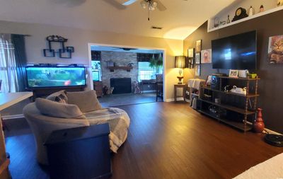 Living room featuring lofted ceiling, bamboo flooring, a fireplace, and ceiling fan | Image 3