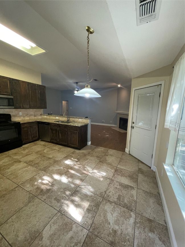 Kitchen with vaulted ceiling, range, dishwasher, sink, and dark brown cabinetry | Image 6