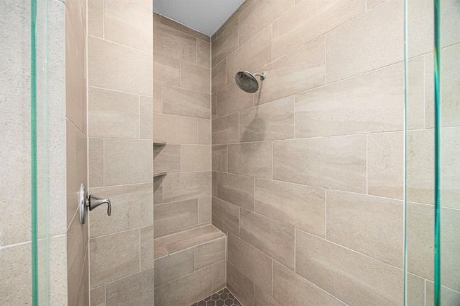 Large walk in shower with bench. | Image 33