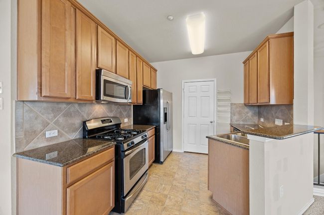 Kitchen featuring a peninsula, tasteful backsplash, appliances with stainless steel finishes, and dark stone countertops | Image 13