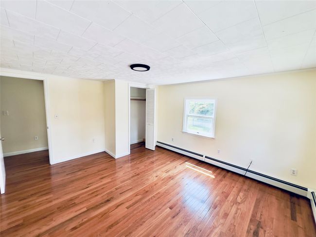 Empty room featuring a baseboard heating unit and wood finished floors | Image 15
