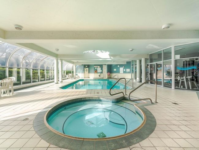 Indoor community pool featuring an in-ground hot tub and a patio | Image 23