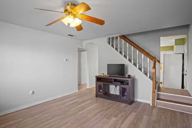 Unfurnished living room with stairs, light wood-style flooring, and ceiling fan | Image 11